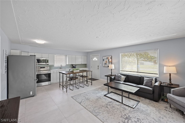 living room featuring sink, light tile floors, and a textured ceiling