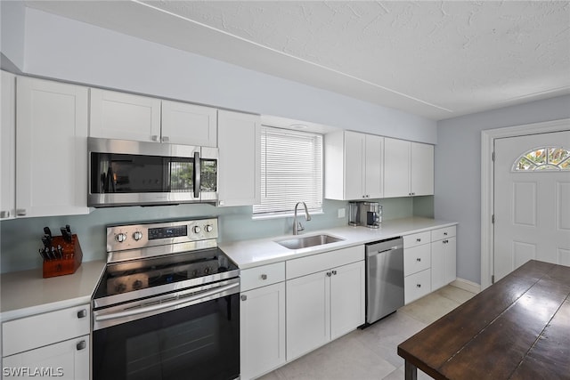 kitchen with appliances with stainless steel finishes, white cabinetry, sink, and plenty of natural light