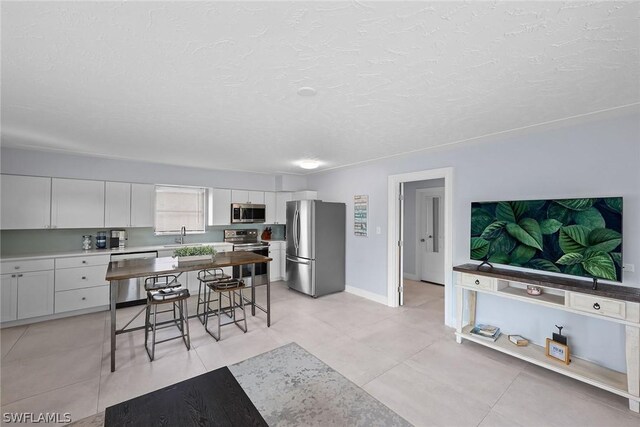 kitchen featuring stainless steel appliances, white cabinets, light tile flooring, and a textured ceiling