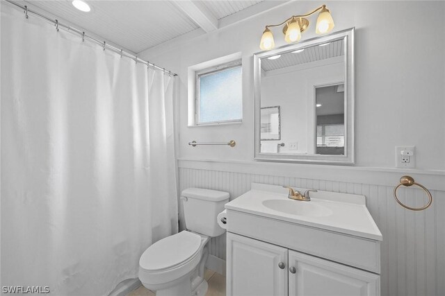 bathroom with beam ceiling, vanity with extensive cabinet space, and toilet