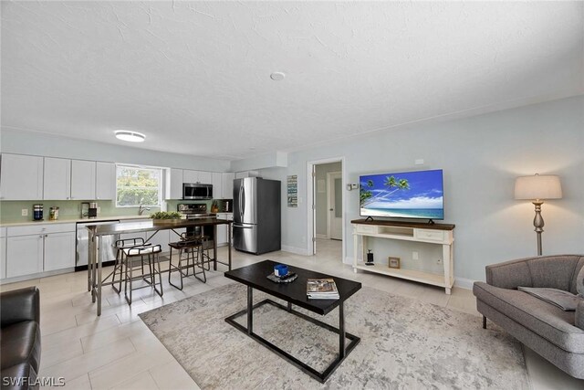 living room featuring sink, a textured ceiling, and light tile floors