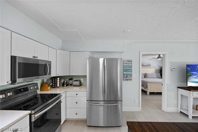 kitchen featuring appliances with stainless steel finishes, white cabinetry, light wood-type flooring, and ceiling fan