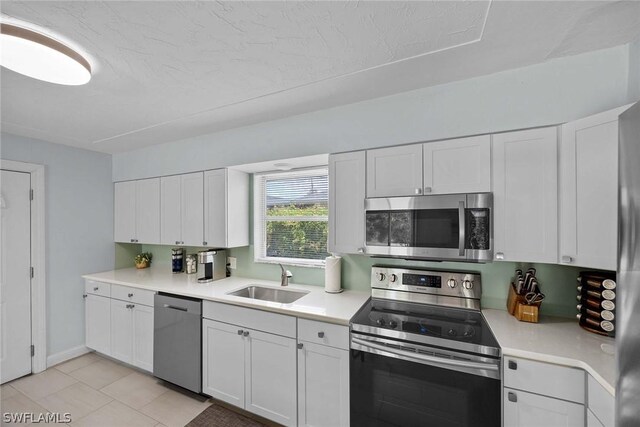 kitchen featuring white cabinetry, sink, light tile flooring, and stainless steel appliances