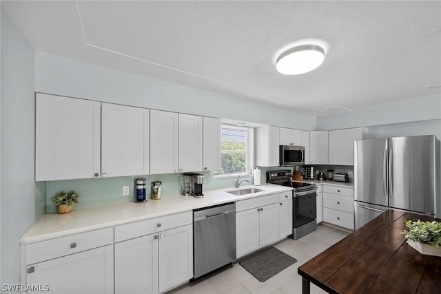 kitchen featuring stainless steel appliances, sink, white cabinetry, and light tile floors