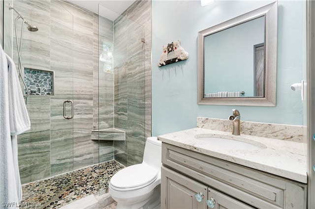 bathroom with a shower with shower door, toilet, and vanity