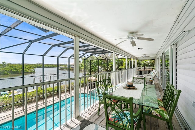 sunroom / solarium featuring ceiling fan and a water view