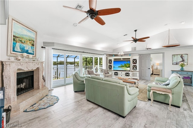 living room with ceiling fan, vaulted ceiling, a fireplace, and light wood-type flooring