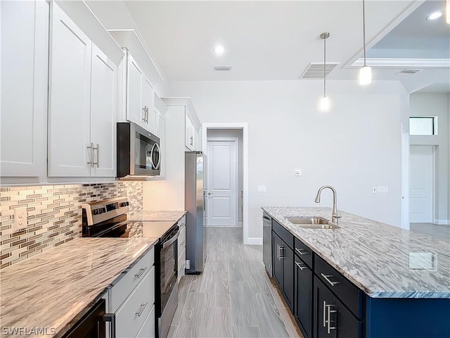 kitchen with appliances with stainless steel finishes, pendant lighting, white cabinetry, sink, and decorative backsplash