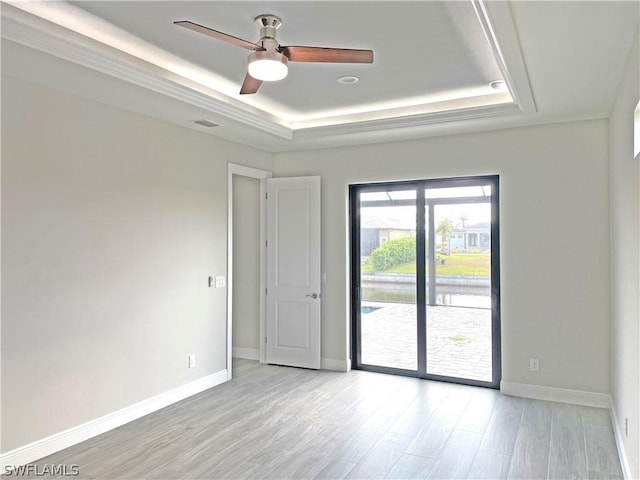 unfurnished room featuring a tray ceiling, light hardwood / wood-style floors, and ceiling fan