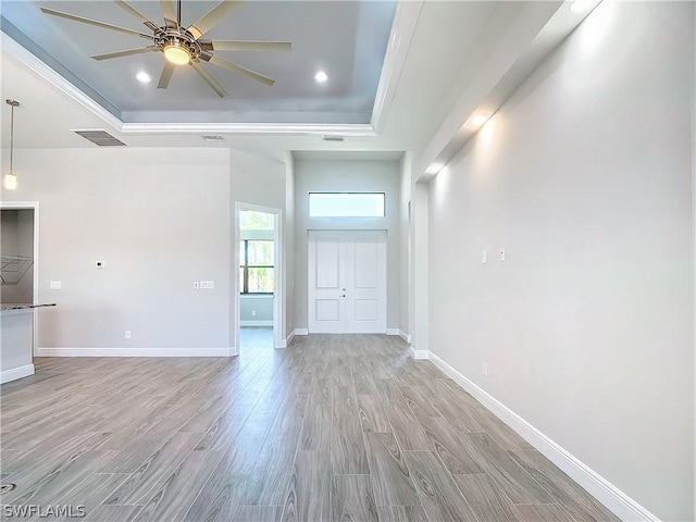 unfurnished living room featuring ceiling fan, a raised ceiling, and light hardwood / wood-style flooring