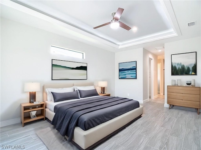 bedroom with ceiling fan and a raised ceiling