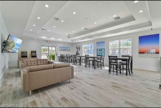 living room featuring a tray ceiling, ornamental molding, and light hardwood / wood-style floors