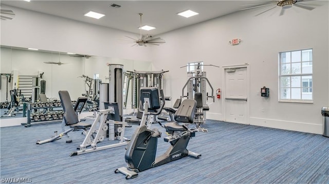 gym featuring carpet, ceiling fan, and a high ceiling