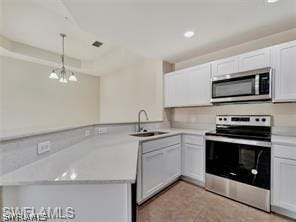 kitchen with stainless steel appliances, white cabinetry, sink, and decorative light fixtures