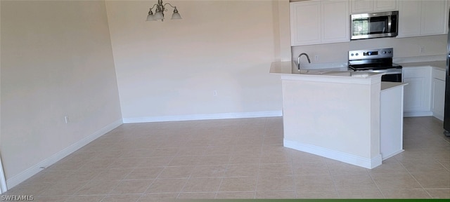 kitchen featuring decorative light fixtures, light tile patterned floors, kitchen peninsula, stainless steel appliances, and white cabinets