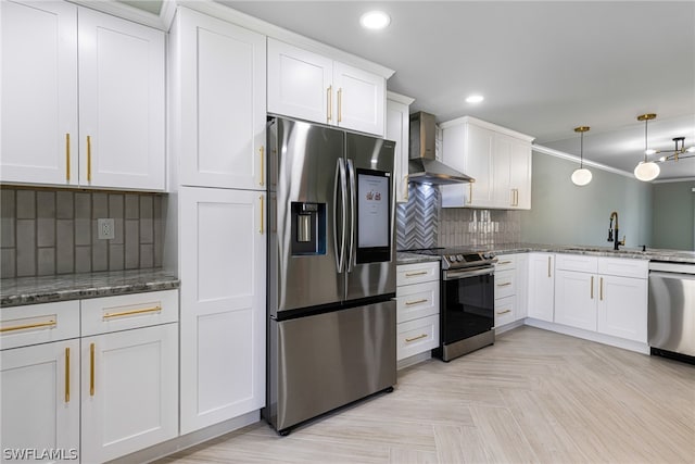 kitchen with stainless steel appliances, tasteful backsplash, wall chimney exhaust hood, white cabinets, and sink