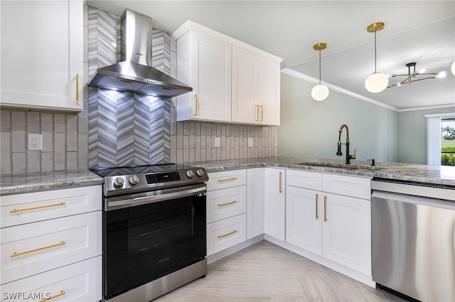 kitchen featuring appliances with stainless steel finishes, white cabinets, sink, wall chimney range hood, and tasteful backsplash