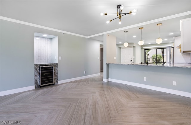 unfurnished living room with light parquet flooring, wine cooler, and ornamental molding