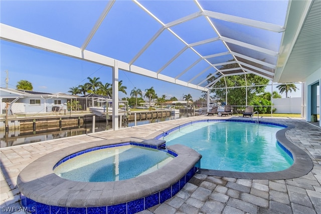 view of pool with a patio area, glass enclosure, and an in ground hot tub