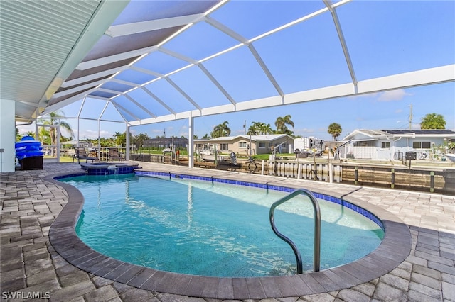 view of pool featuring a patio, glass enclosure, and an in ground hot tub