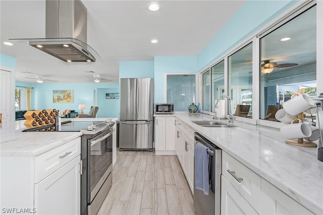 kitchen with white cabinetry, appliances with stainless steel finishes, island exhaust hood, sink, and ceiling fan