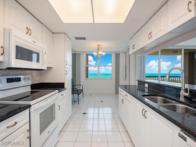 kitchen with white appliances, a sink, visible vents, white cabinets, and dark stone counters