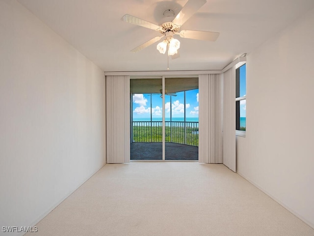 empty room featuring a ceiling fan, a water view, and carpet flooring