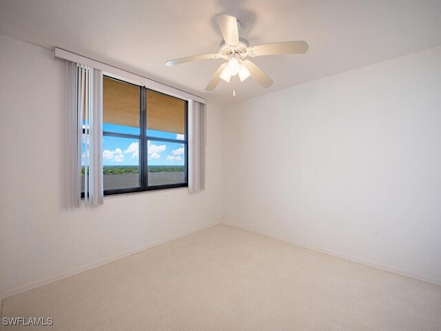 empty room featuring a ceiling fan and carpet