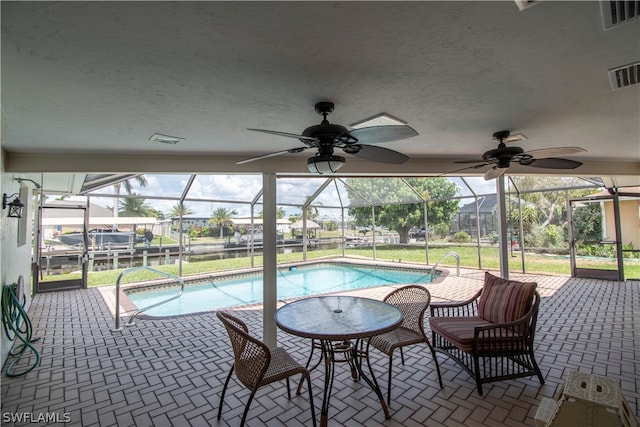 view of pool with a patio, ceiling fan, and glass enclosure