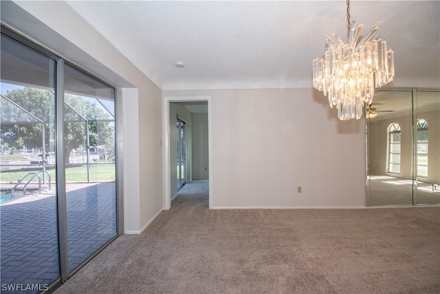 empty room featuring ceiling fan with notable chandelier, dark carpet, and a textured ceiling