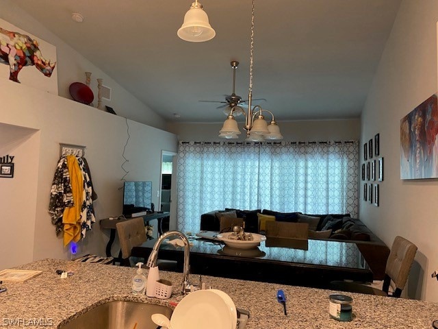 kitchen featuring sink, plenty of natural light, vaulted ceiling, and light stone countertops