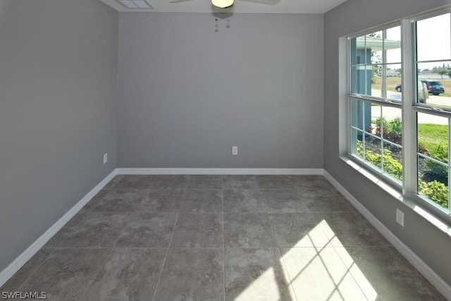 spare room featuring ceiling fan and dark tile floors