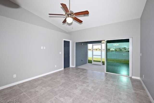 tiled empty room with vaulted ceiling, ceiling fan, and a water view