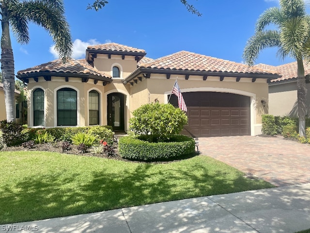 mediterranean / spanish home featuring a garage and a front lawn