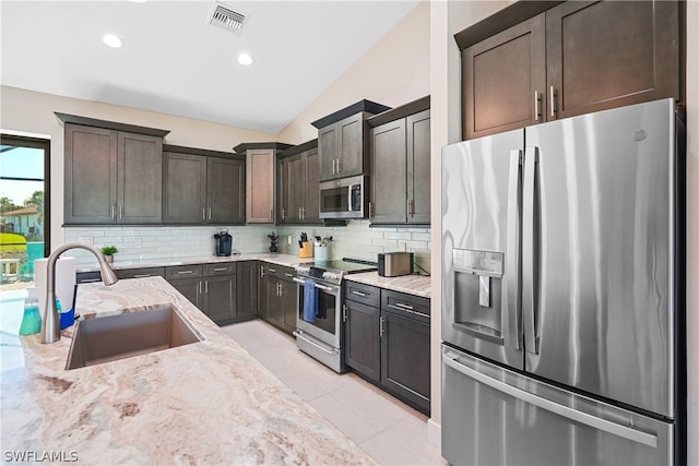 kitchen with appliances with stainless steel finishes, light tile floors, sink, tasteful backsplash, and lofted ceiling