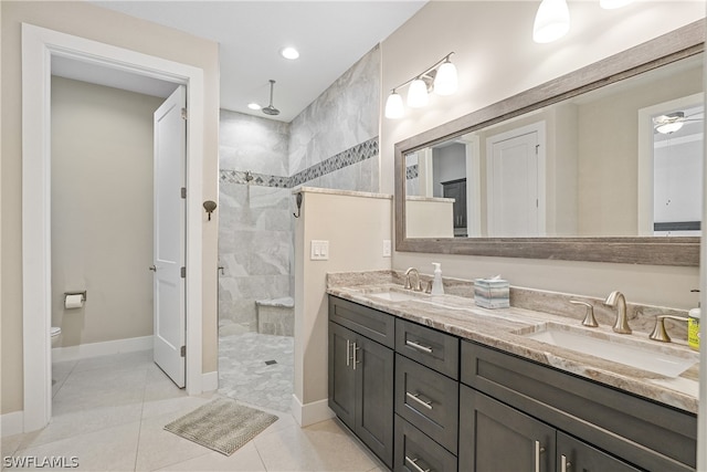 bathroom with tiled shower, toilet, dual vanity, and tile flooring