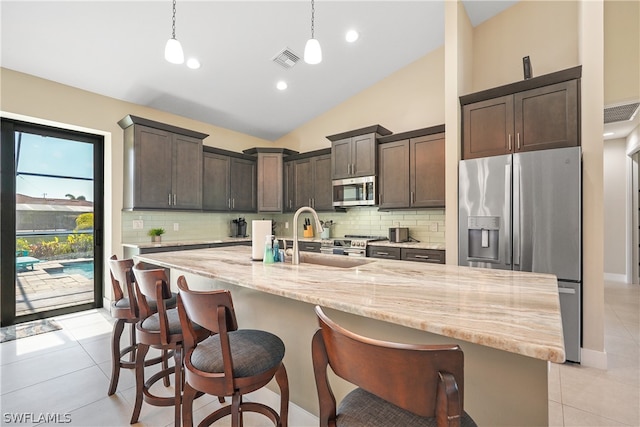 kitchen featuring tasteful backsplash, a kitchen island with sink, sink, and decorative light fixtures