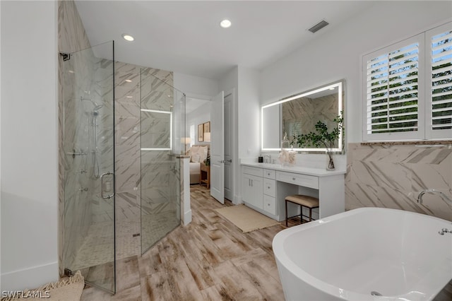 bathroom with vanity, hardwood / wood-style flooring, tile walls, and plus walk in shower