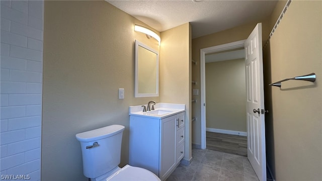 bathroom with toilet, tile flooring, vanity, and a textured ceiling