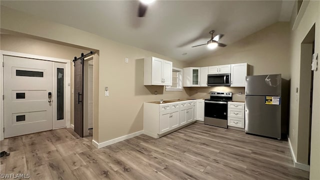 kitchen featuring vaulted ceiling, appliances with stainless steel finishes, ceiling fan, and a barn door