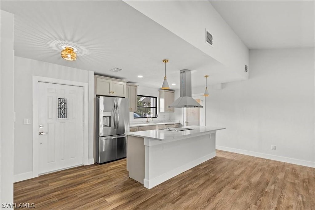 kitchen featuring stainless steel fridge with ice dispenser, island range hood, black electric stovetop, decorative light fixtures, and a center island