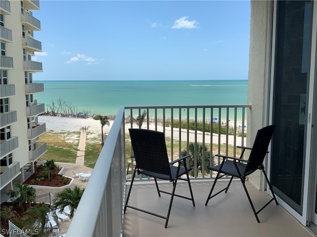 balcony featuring a view of the beach and a water view