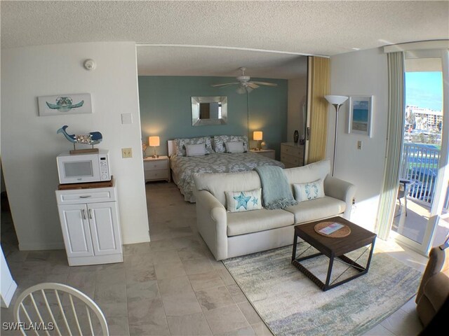 bedroom featuring access to exterior, a textured ceiling, and ceiling fan