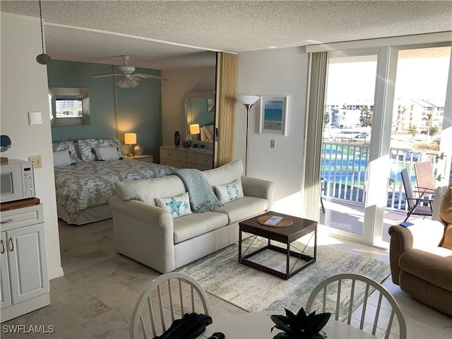 bedroom featuring ceiling fan, access to exterior, and a textured ceiling