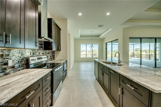 kitchen with backsplash, a tray ceiling, wall chimney exhaust hood, sink, and stainless steel electric stove