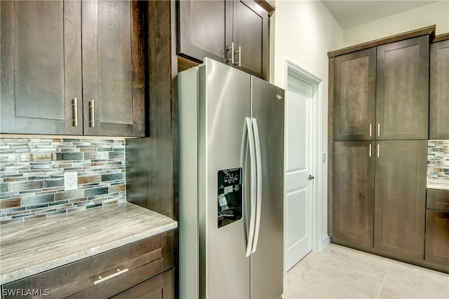 kitchen with tasteful backsplash, dark brown cabinets, stainless steel refrigerator with ice dispenser, and light tile flooring