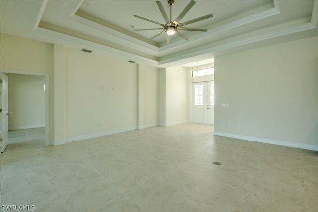 spare room featuring a raised ceiling, ceiling fan, and light tile flooring