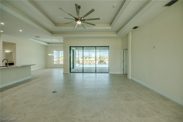 tiled spare room with a raised ceiling, ceiling fan, sink, and ornamental molding