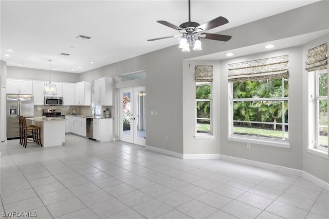 kitchen featuring hanging light fixtures, appliances with stainless steel finishes, light tile floors, a kitchen island, and ceiling fan