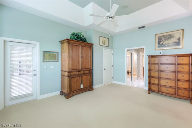 carpeted bedroom with a raised ceiling and ceiling fan